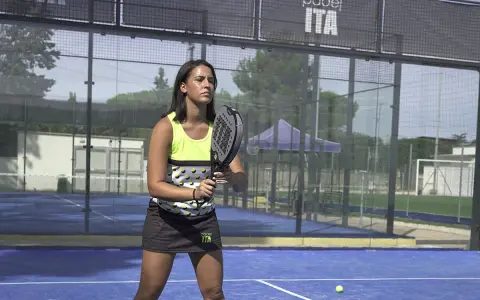 Giocatrice di padel con racchetta, pronta a scendere in campo. Ecco come vestirsi per giocare a padel: top tecnico e gonna sportiva.