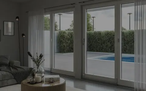 Soggiorno moderno con grandi vetrate che si affacciano su una piscina. L'isolamento acustico garantisce tranquillità.