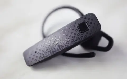 Czarna słuchawka Bluetooth z fakturą kółek, gotowa do połączenia. Dowiedz się, jak sparować słuchawki z telefonem.