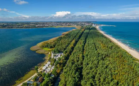 Widok z lotu ptaka na Półwysep Helski: las, kemping, plaża i morze. W oddali widać miasto i latarnię morską. Warto pamiętać o historii, w tym o bunkrach Hel.