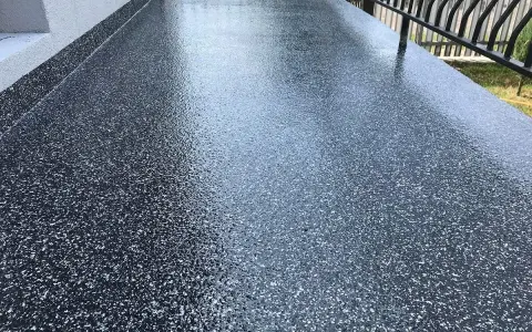 Nowy, błyszczący balkon z żywicą epoksydową. Ciemna posadzka z drobinkami tworzy nowoczesny wygląd.