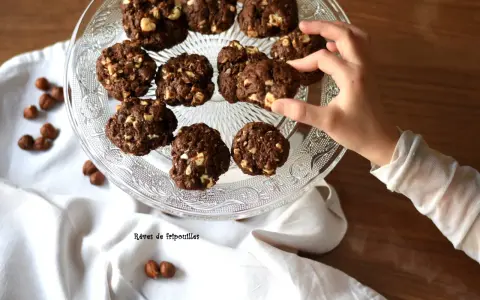 Délicieux cookies au chocolat et noisettes, parfaits pour savoir que faire avec un reste de ganache au chocolat. Une main en prend un.