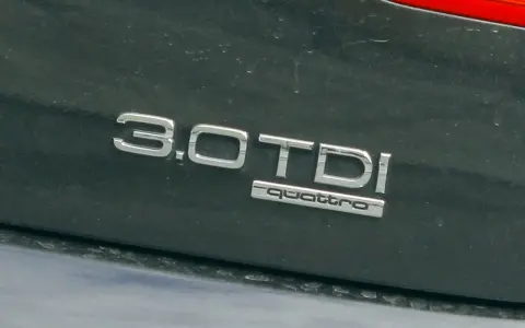 Napis "3.0 TDI quattro" na ciemnym lakierze. Ta pojemność silnika sugeruje moc i osiągi.