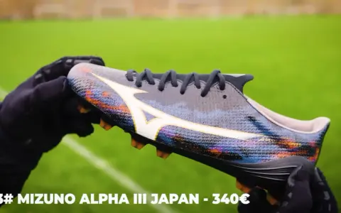 Ręce w rękawiczkach trzymają kolorowe korki Mizuno Alpha III Japan, które mogą być najlepszymi korkami na świecie.