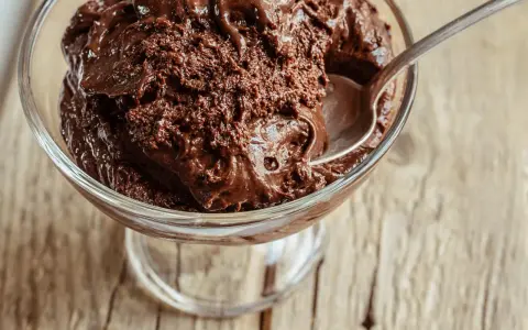 Une cuillère s'enfonce dans une coupe de mousse au chocolat au lait onctueuse, prête à être dégustée.