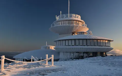 Lodowy pałac na szczycie w Karkonoszach. Budynek obserwatorium pokryty szronem, otoczony zimowym krajobrazem.