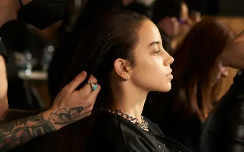 Stylista układa włosy modelki, ukazując olśniewające olaplex efekty: jedwabistość i blask.