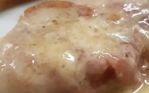 Cotoletta alla bolognese succulenta, con prosciutto e formaggio fuso, un classico della cucina emiliana.