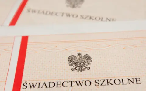 Zbliżenie na świadectwo szkolne z godłem Polski. Czerwono-biały pasek po lewej stronie.
