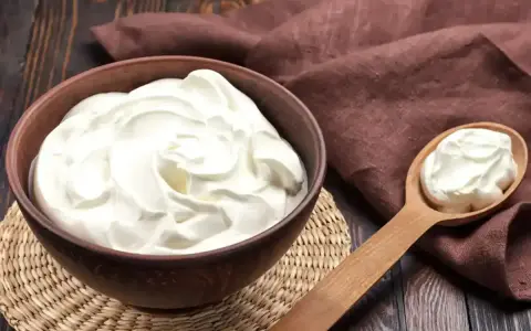 Un bol de crème onctueuse, parfaite pour une crème diplomate, avec une cuillère en bois remplie de cette douceur.
