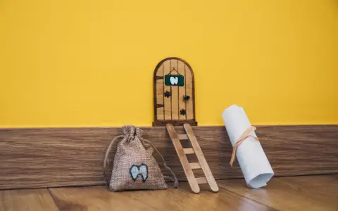 Puerta de madera para hacerla del ratoncito pérez, con una bolsa de dientes y un pergamino.