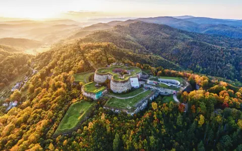 Twierdza na wzgórzu otoczona jesiennym lasem, przypominająca o historii gór blisko Wrocławia.