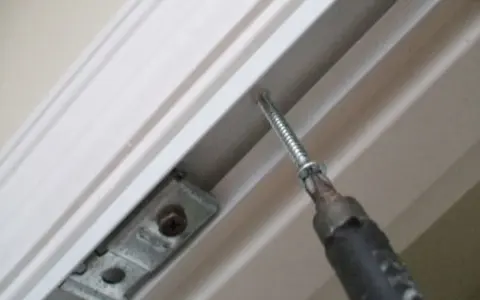 Screwdriver installing a bracket for how to install bifold doors.