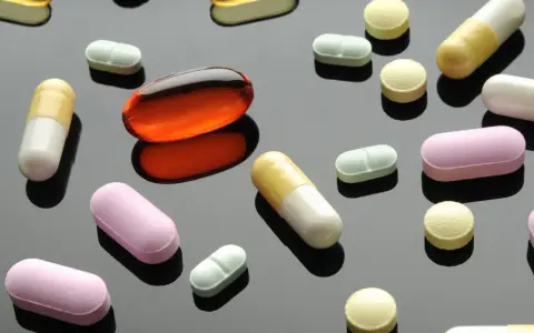 Varie pillole e capsule colorate, tra cui una grande capsula arancione trasparente. Un'immagine che fa riflettere sulla terapia biologica cos'è.