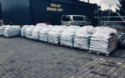 Duże worki z materiałem budowlanym przed sklepem drogowym. Zastanawiasz się, ile kosztuje asfalt? Tutaj znajdziesz odpowiedź.