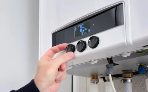 Mano che regola la temperatura su una caldaia a corrente. Il display mostra 76°C.