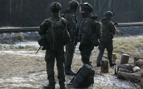 Szeregowi w wojsku patrolują teren przy torach kolejowych, gotowi do akcji.