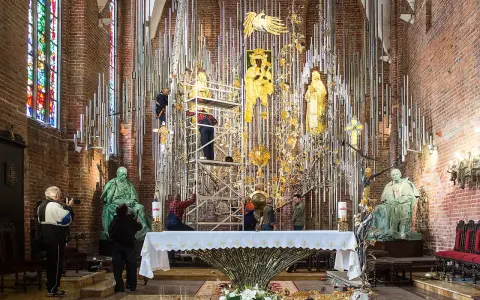 Prace przy ołtarzu w Bazylice św. Brygidy. Ludzie na rusztowaniach montują złote elementy dekoracji.