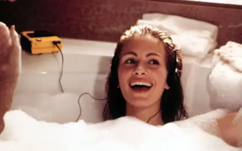 Julia Roberts lacht in einer Schaumbadewanne, hört Musik über Kopfhörer. Sie fragt sich, wie oft Haare waschen wohl nötig ist, um so strahlend auszusehen.