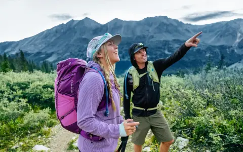 Deux randonneurs s'émerveillent devant un panorama de amm montagne. L'un d'eux pointe du doigt un sommet lointain.