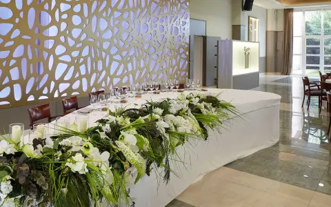 Elegante mesa presidencial boda con arreglos florales blancos y verdes, velas y copas.
