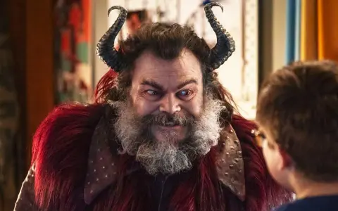 Jack Black med horn och rött päls, en karaktär från filmer med Jack Black, tittar på ett barn.