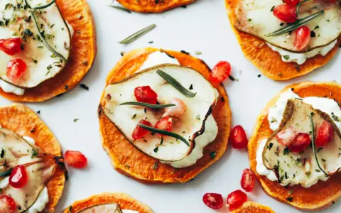 Deliciosas rodajas de boniato asado con queso cremoso, pera, granada y romero. Ideales para recetas con boniato.