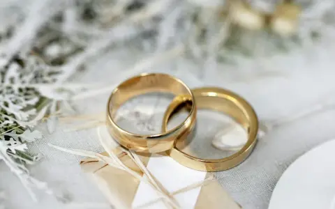 Due fedi dorate intrecciate su uno sfondo delicato. Pensare a cosa incidere sulle fedi è un passo importante per personalizzare questo simbolo d'amore.