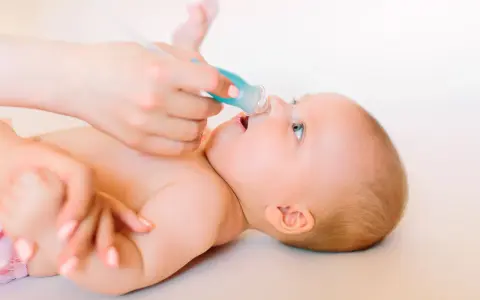 Manos cuidadosas realizan lavado nasal a un bebé.