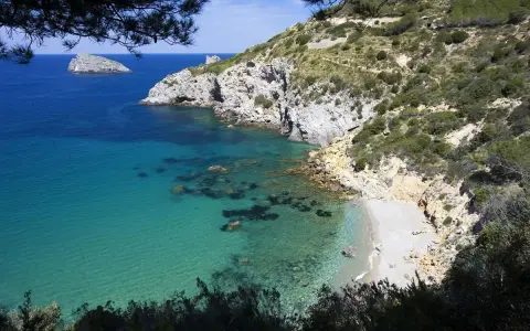 La cala del gesso, Monte Argentario, offre acque cristalline e una spiaggia appartata tra rocce e macchia mediterranea.