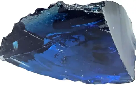 Fragmento de obsidiana azul con reflejos profundos y texturas irregulares, como un trozo de cielo nocturno solidificado.