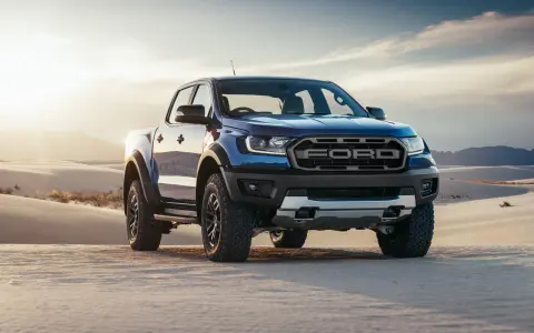 Niebieski Ford Ranger Raptor przemierza piaszczyste wydmy o zachodzie słońca.