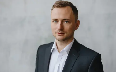 Mężczyzna w garniturze i białej koszuli, idealny przykład, jak zrobić zdjęcie biznesowe w domu.