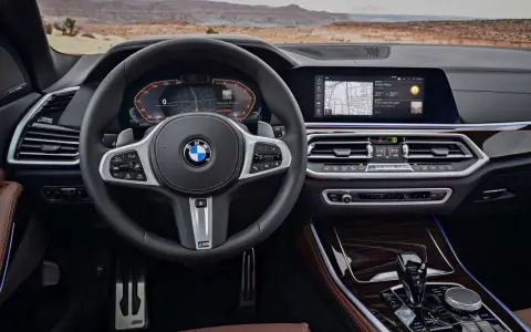 Wnętrze BMW z systemem BMW Live Cockpit Professional. Kierownica, ekran nawigacji i panel klimatyzacji.
