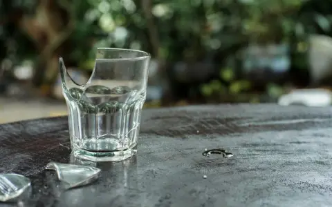 Rozbite szklanki leżą na ciemnym blacie. Pytanie, gdzie wyrzucać szklanki, staje się aktualne.