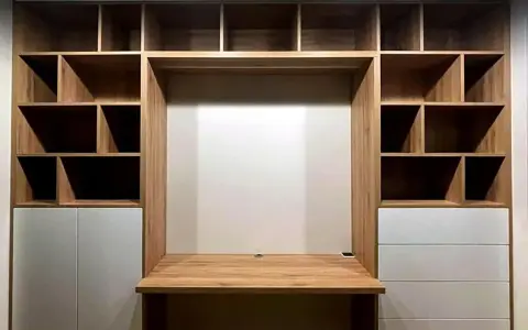 Einbauwand mit Schreibtisch und vielen Fächern. Weiße Schubladen bieten unsichtbaren Stauraum für Ordnung.