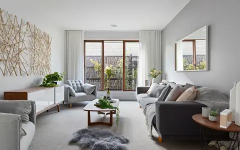 Salones en gris y beige con sofá oscuro, sillón acogedor, mesa de centro de madera y decoración natural.