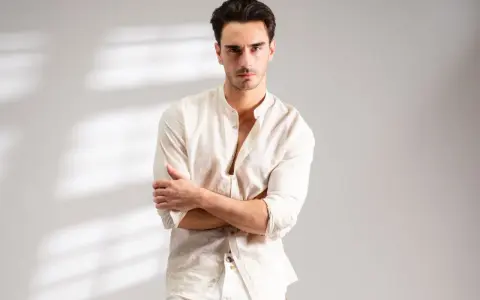 Uomo con outfit bianco e nero, camicia lino con colletto alla coreana e pantaloni chiari.
