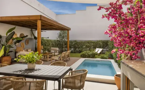 Un patio moderno con piscina, pérgola de madera, zona de estar y comedor exterior. Ideas para decorar un patio con piscina y crear un oasis de relax.