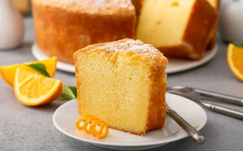 Puszysta babka cytrynowa, oprószona cukrem pudrem, z plasterkami pomarańczy. Idealna na niedzielne popołudnie, gdy szukasz przepisu na babkę wiszącą.