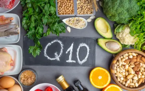 Q10 na tablicy, otoczone produktami bogatymi w koenzym Q10. Warto pamiętać o przeciwwskazaniach przy suplementacji.