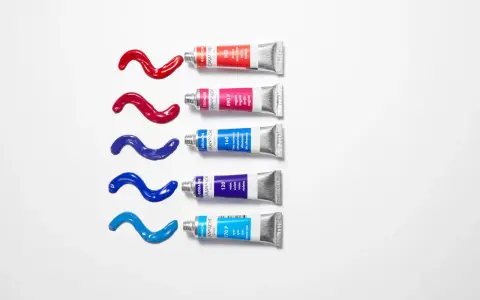 Des tubes de gouache Caran d'Ache rouge, magenta, bleu outremer, violet et cyan, avec des coulées de peinture sur fond blanc. Quelle peinture pour toile ?