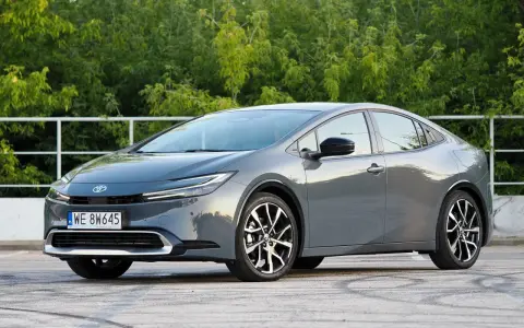 Szary Toyota Prius hybryda na tle zieleni. Zastanawiasz się, ile pali Toyota Prius hybryda? Ten model zachwyca niskim spalaniem.
