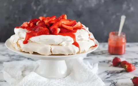 Deliciosa tarta pavlova con fresas frescas y salsa de fresa, lista para ser disfrutada.