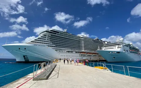 Persone camminano su un molo verso due enormi navi da crociera, pronte per imbarcarsi. Ecco come si sale su una nave da crociera!