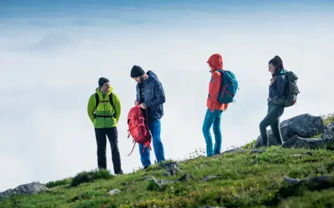 Czterech turystów w górskim krajobrazie, przygotowujących się do wyprawy. To właśnie jest co to trekking – przygoda i odkrywanie.
