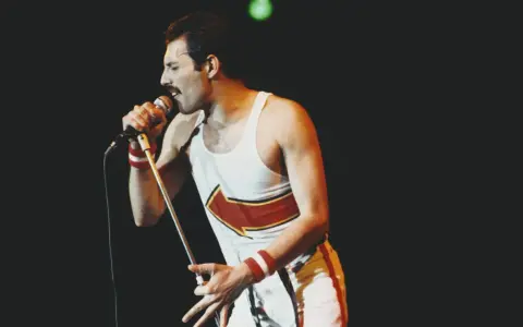 Freddie Mercury, jeden z najlepsi muzycy wszechczasów, śpiewa do mikrofonu na koncercie.