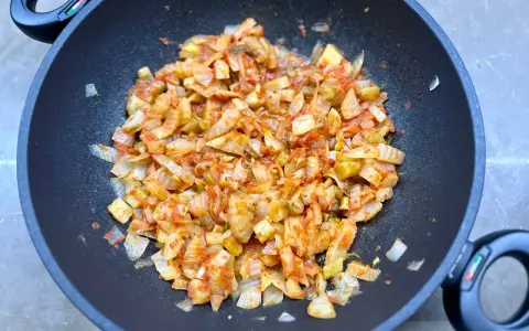 Finocchi in padella, tagliati a pezzi e cotti con pomodoro e spezie, emanano un profumo invitante.