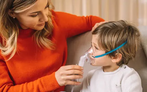 Mamma assiste il bambino con un inalatore per alleviare il broncospasmo.