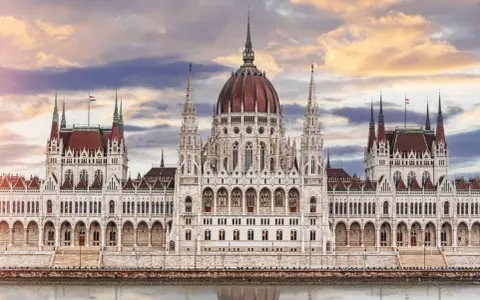 Majestatyczny Parlament w Budapeszcie, jedna z głównych atrakcji turystycznych, odbija się w wodzie.